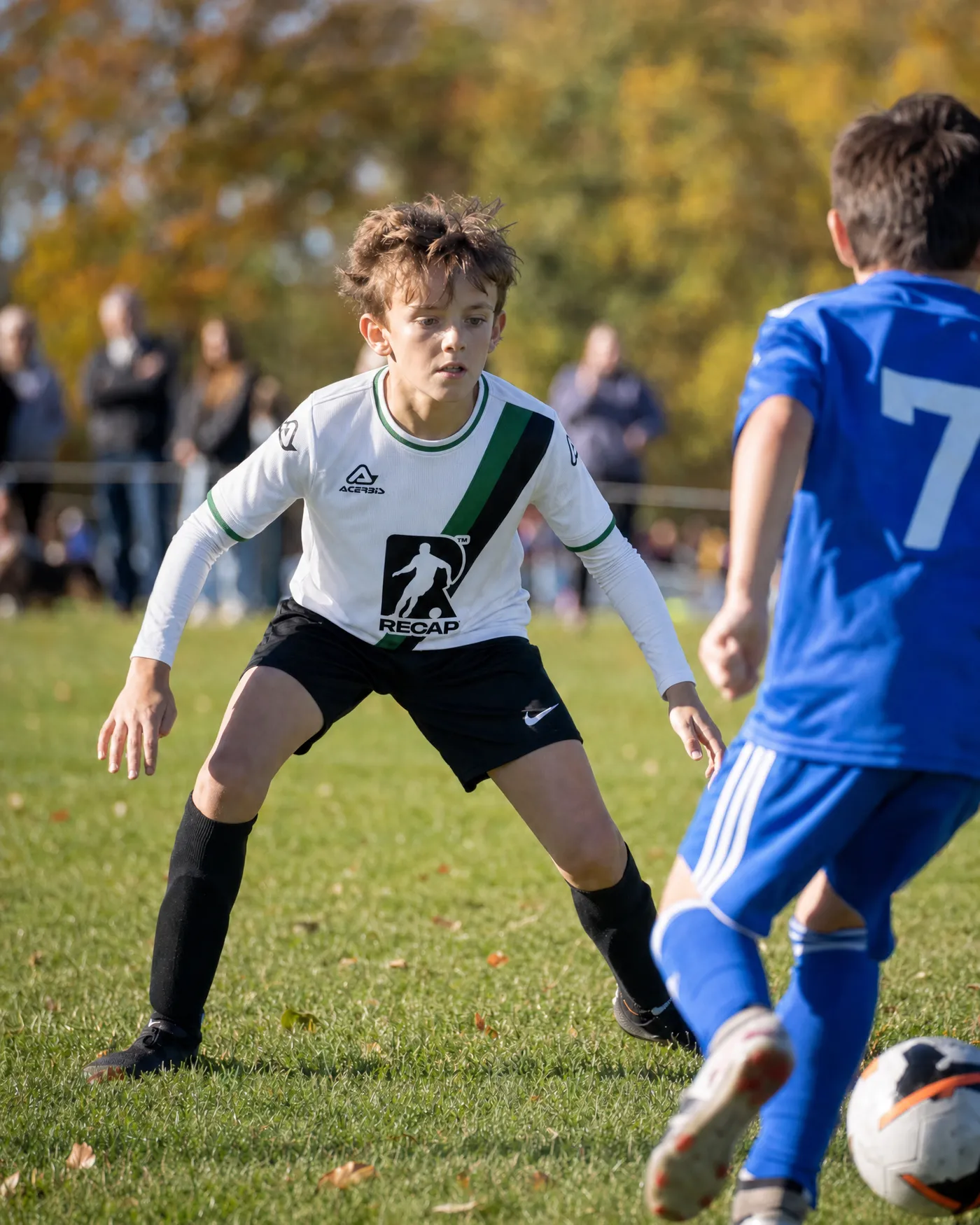 A player in a Recap-sponsored shirt facing up an opponent